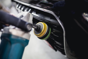 Car detailing - Hands with orbital polisher in auto repair shop. Selective focus.