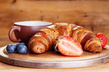 Coffee cup, fresh croissant and berries 