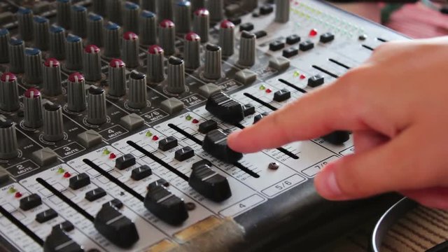 DJ console or mixer, the hand presses the levers and buttons of remote