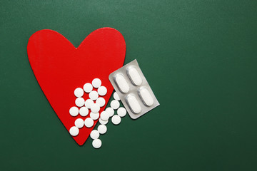 White pills are good for heart on green background, closeup.