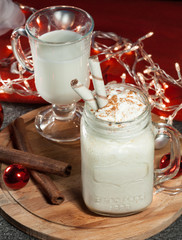 Christmas eggnog in the glass of mulled wine with cream and cinnamon and Christmas garland