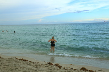 Fototapeta na wymiar View of woman standing in Atlantic ocean and going to swim