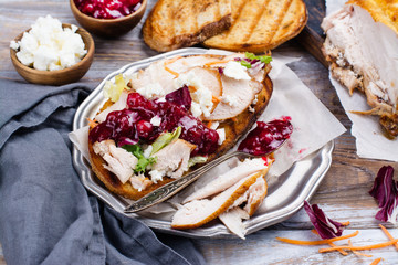 Homemade leftover thanksgiving day sandwich with turkey, cranberry sauce, feta cheese and vegetables