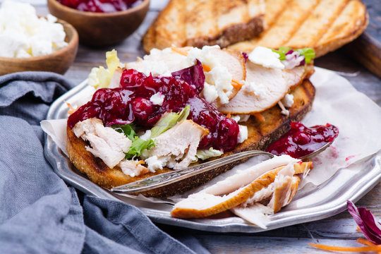Homemade leftover thanksgiving day sandwich with turkey, cranberry sauce, feta cheese and vegetables