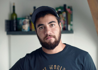 Hipster mit cappy in der K&uuml;che, junger Mann mit Vollbart muss kochen, Junggeselle