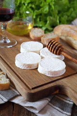 Fototapeta na wymiar Soft French goat cheese Rocamadour, bread, honey, lettuce and glass of red wine.