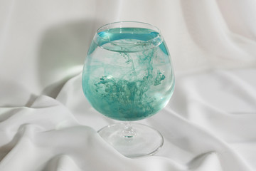 Бирюзовая акварель в стакане воды. Цветная смесь.