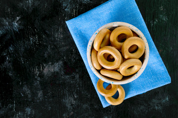 Small crispy bagels in a ceramic bowl on a black background. Snack.