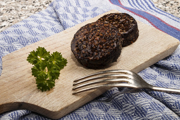 grilled irish black pudding made with oatmeal on a wooden board with knife