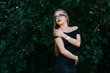 Portrait of beautiful woman in black dress, glasses and red lipstick