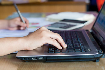 woman hand calculate cost and expenses and using laptop for search data result