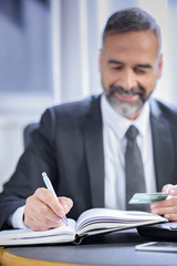 Senior business man writing down credit card information in his personal agenda