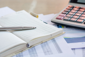 Close up pen on finance report and calculator on table office.