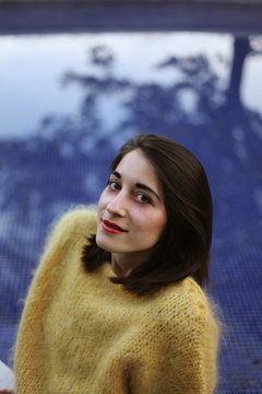 Beautiful Woman In  A Yellow Sweater Sitting Near An Open Swimming Pool