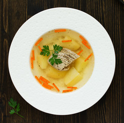 Meat and vegetable soup with parsley in a bowl on a dark background. View from above.