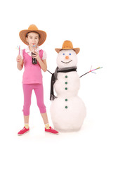 Cute girl holding a cola bottle near a snowman with scarf and hat