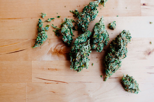 Marijuana buds spread out on a wooden table.
