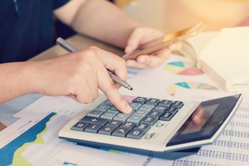 close up hand woman calculating about cost and using smartphone searching data in office.