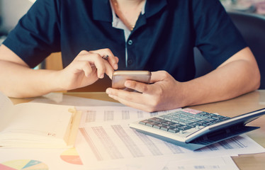 Fototapeta premium close up hand woman calculating about cost and using smartphone searching data in office.