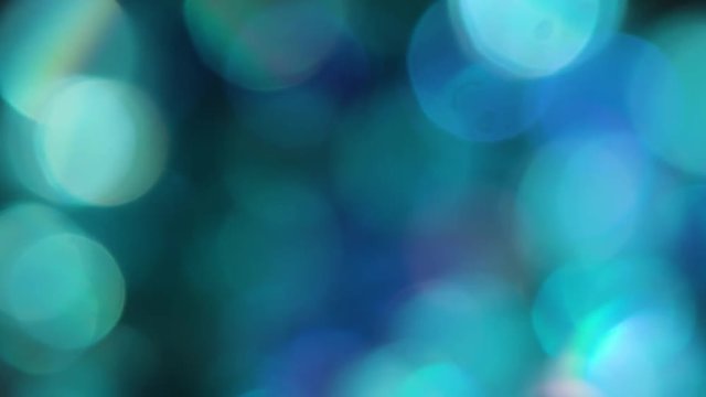 The Circles Bokeh stock video features a circle rotation in a clockwise direction of blurred turquoise and blue lights. You can use it as an overlay for creative video effects, artistic videos, and as