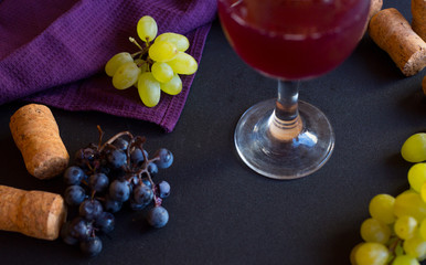 Wineglasses with grapes and corks on dark background with copy space