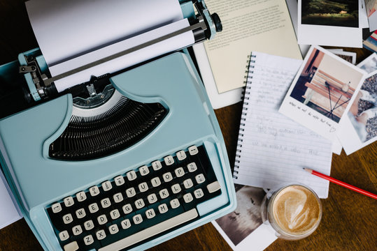 A blue retro vintage typewriter surrounded by the inspiration of writing, with coffee