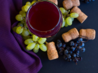 Wineglasses with grapes and corks on dark background with copy space