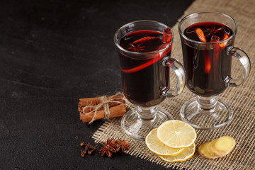 Mulled wine banner. Glasses with hot red wine and spices on dark background. Modern dark mood style.