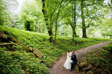 Magnificent bride sitting on a lap of her husband in the forest on a wedding day.