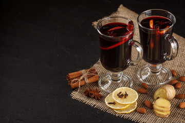 Mulled wine banner. Glasses with hot red wine and spices on dark background. Modern dark mood style.