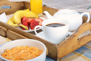 Breakfast tray with coffee, orange juice, cereals and fruits.