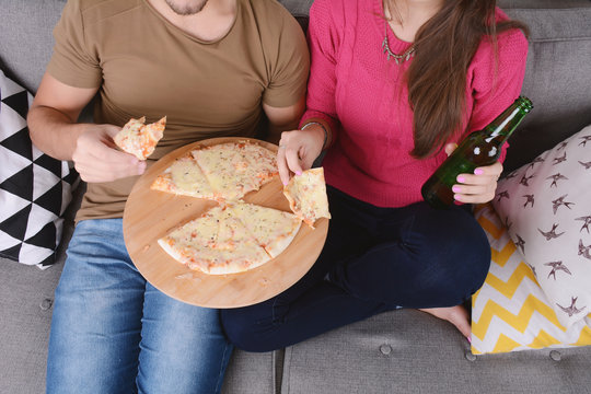 Couple drinking beer and eating pizza.