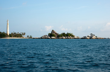 White lighthouse standing on an island in Belitung at daytime with no people around.