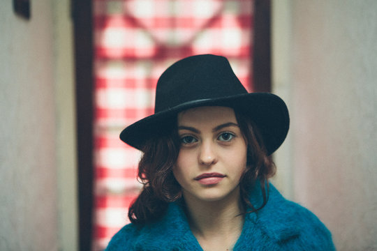 Portrait of a beautiful young woman wearing a hat in a corridor