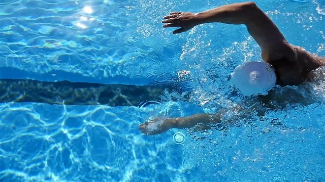 A man swimming freestyle in a pool, slow motion
