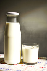 a bottle of organic milk and a glass of milk next to it