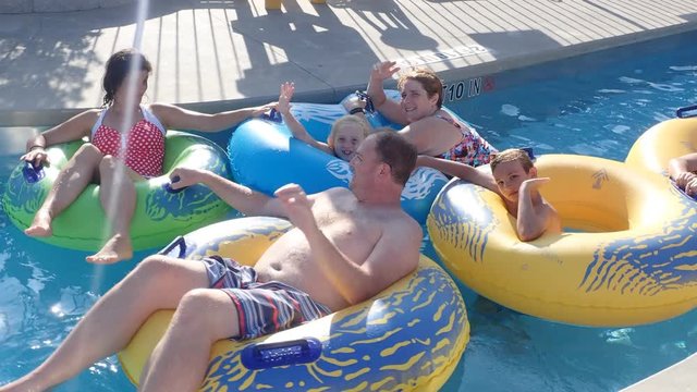 Family Relaxing On Vacation In Lazy River At Waterpark In Resort