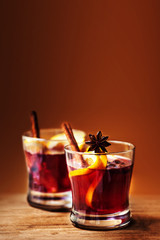 Hot wine for winter and Christmas Holidays with orange and spices on wooden  background  with copy space..