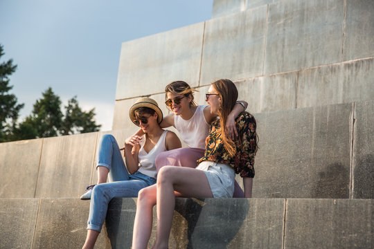 Three girlfriends sitting on the monument having fun