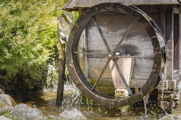 Small wooden water mill spinning in a small pond, decoration in the garden