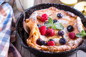 Dutch baby pancake with apples and cinnamon in a pan on a table close-up