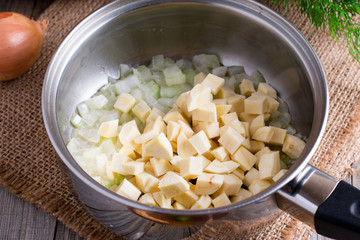 Raw potatoes sliced in a saucepan on a wooden background