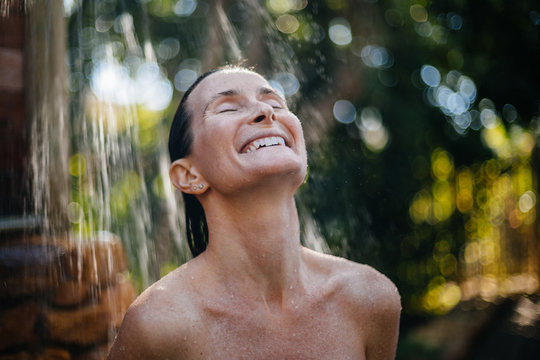 Beautiful woman in outdoor shower surrounded by nature