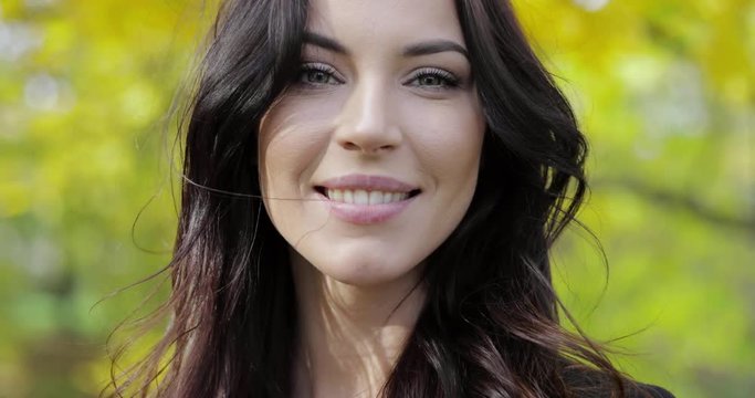 Pretty happy-looking woman looking at camera and smiling during her walk in beautiful autumn park.