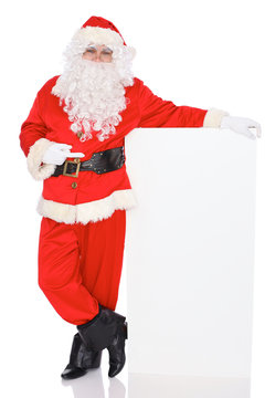 Santa Claus pointing on blank white wall, advertisement banner with copy space. Isolated on white background. Full length portrait
