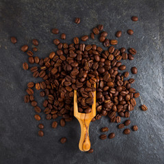 Coffee beans in a wooden scoop on slate plate background