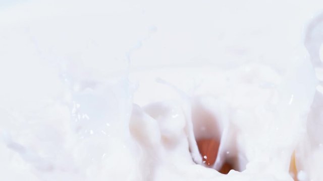  Fresh almonds dropping into bowl of milk with a splash in slow motion