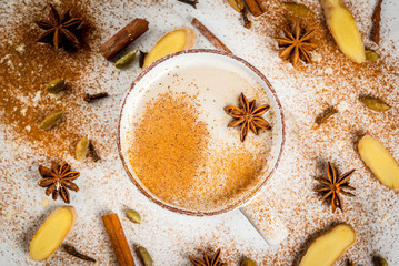 Obraz na płótnie Canvas Traditional indian masala chai tea with spices - cinnamon, cardamom, anise, white background. Top view copy space
