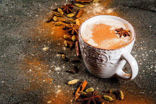 Traditional indian masala chai tea with spices - cinnamon, cardamom, anise, dark stone background. Copy space