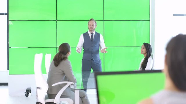  Corporate business team in a meeting with green screen video wall behind